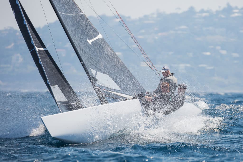 5.5 Metre sailboat with crew hanging over side of the boat