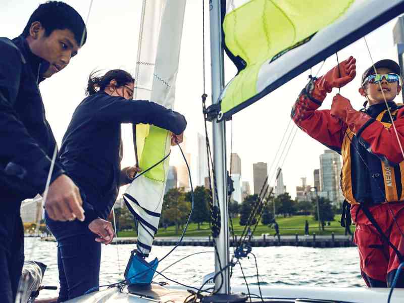Three kids rigging up boat sailing.