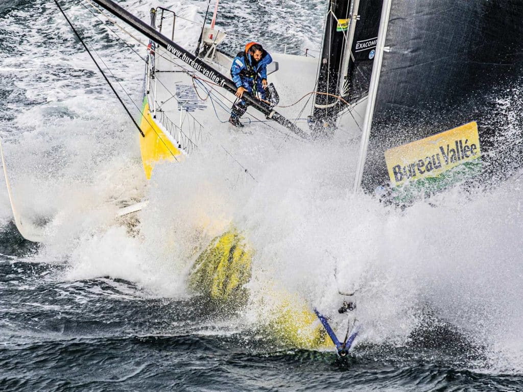 A man pilots a sailboat through rough waters.