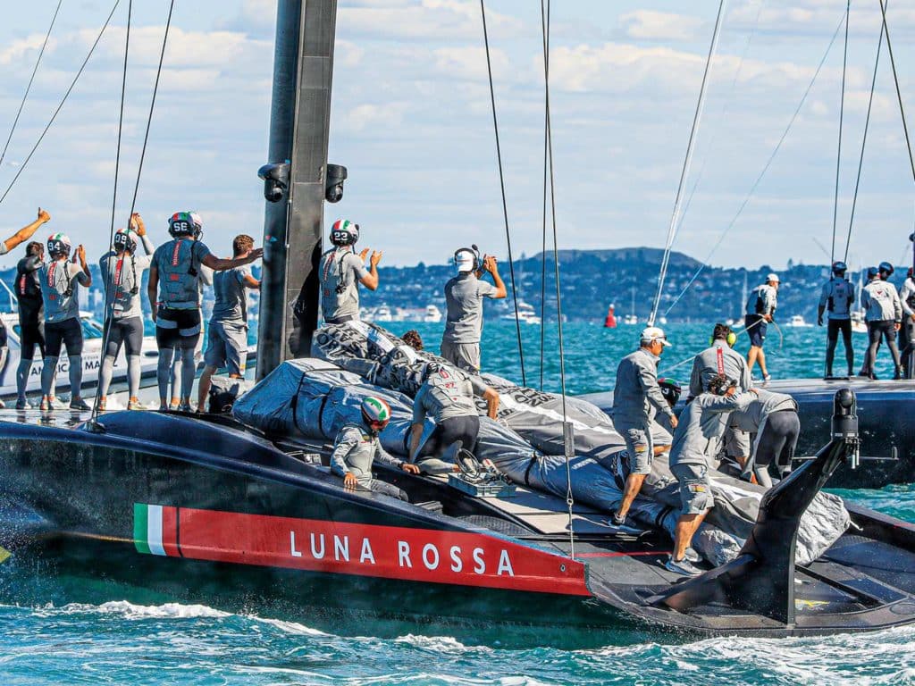 A group of people standing on the capsized sailboat.