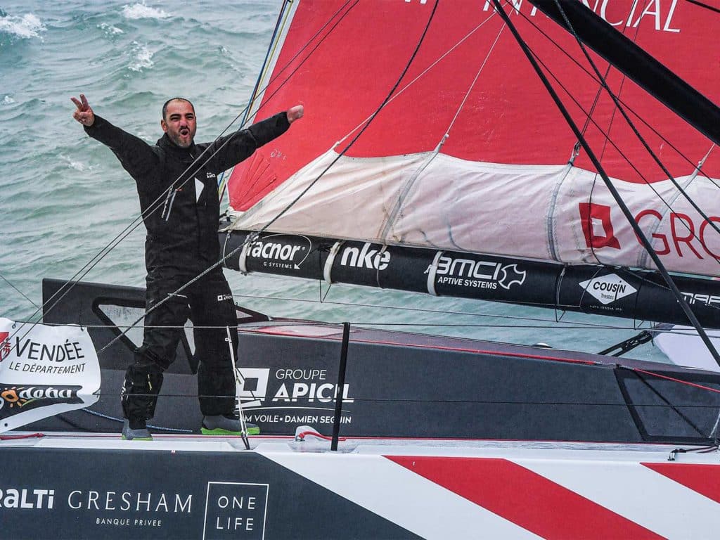 Paralympian Damien Seguin celebrating on top of a sailboat.