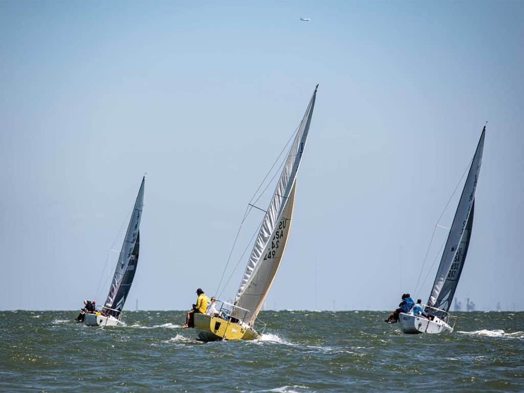 Three sailboats racing across the water.