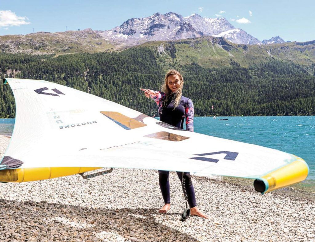 A woman standing next to a kiteboard.